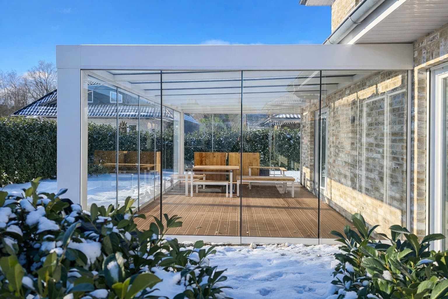 Cube in Weiß mit Glasschiebewänden, im Schnee, Blick auf eine Holzterrasse darin