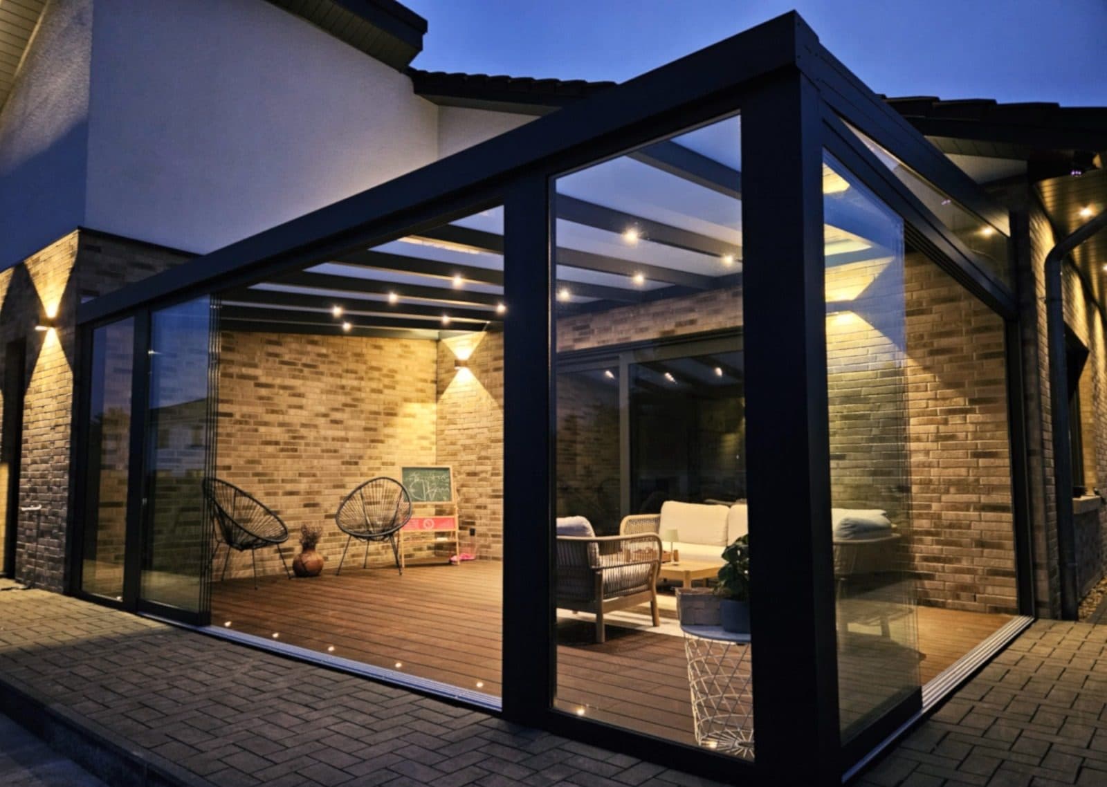 Gebaute Terrassenüberdachung am Abend: Glasdach, Glasschiebewände, Spots in den Sparren